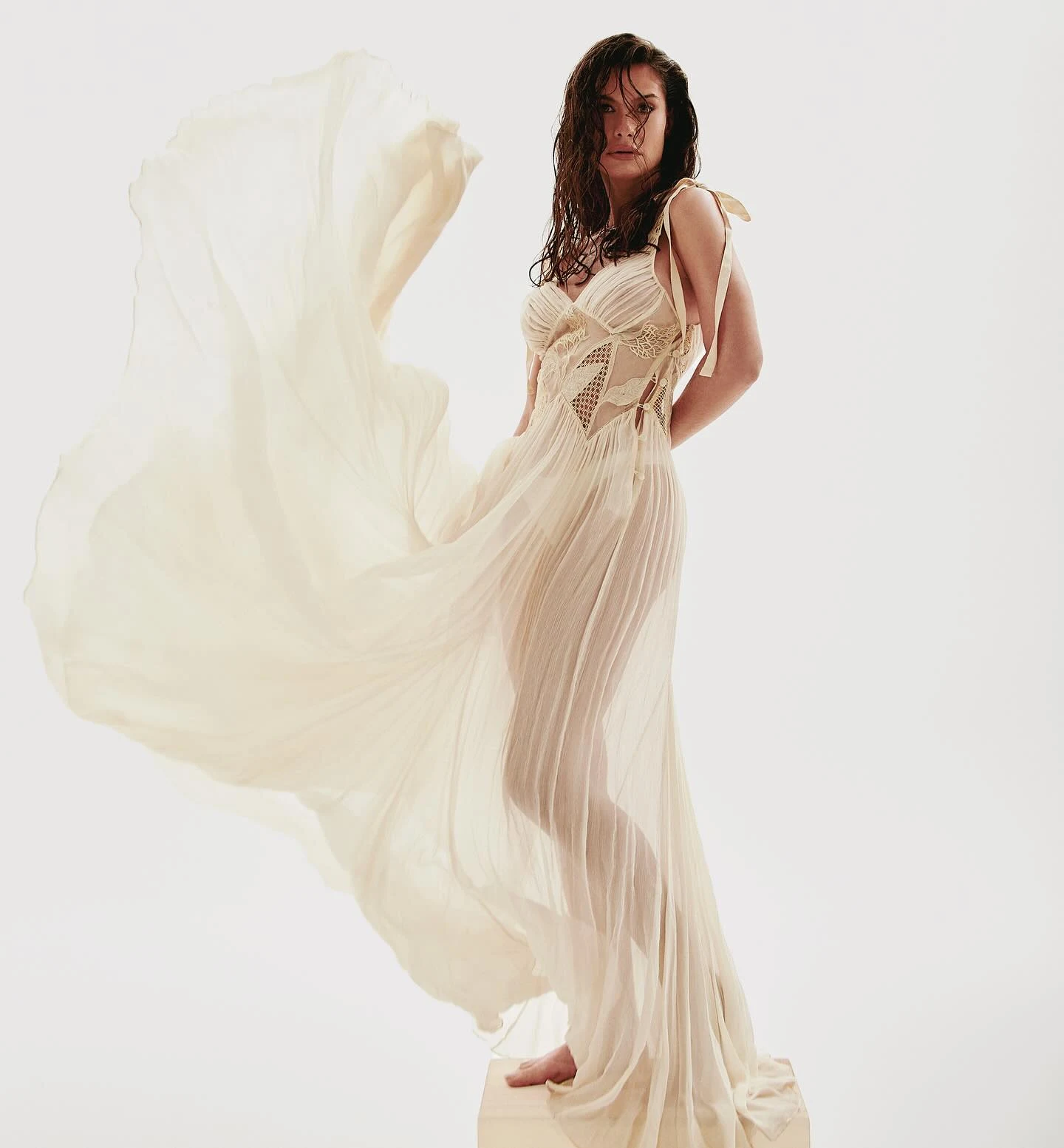 Alinne Moraes com vestido off-white fluido em movimento sobre fundo claro
