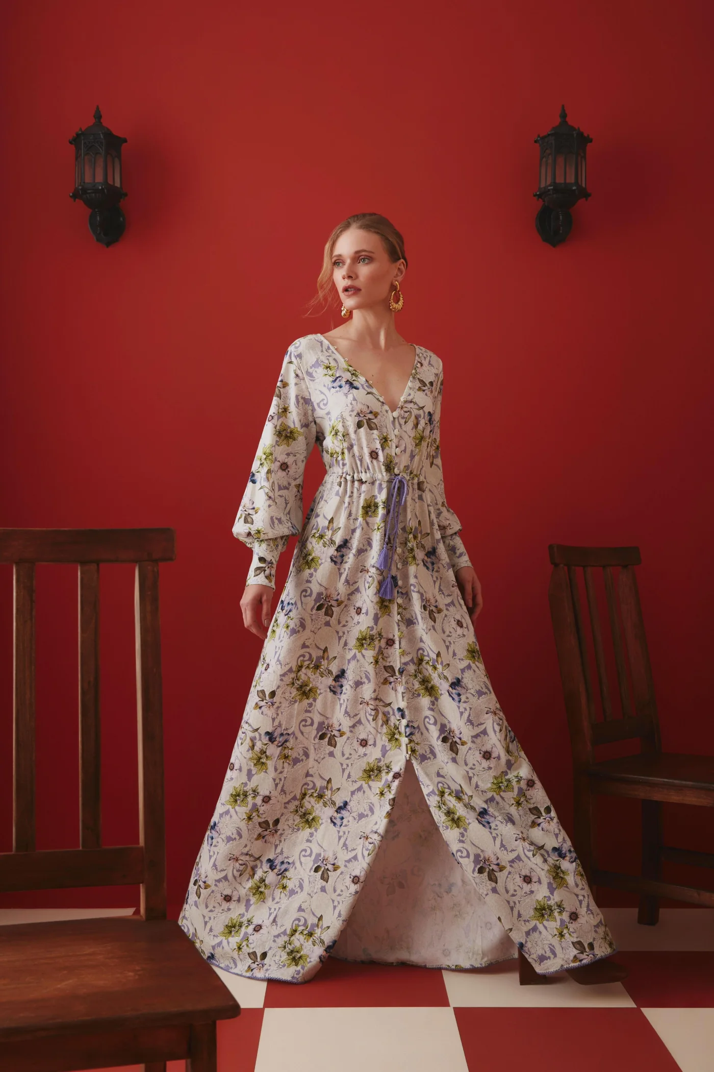Thais Custodio em vestido floral longo diante de parede vermelha para Lalibela