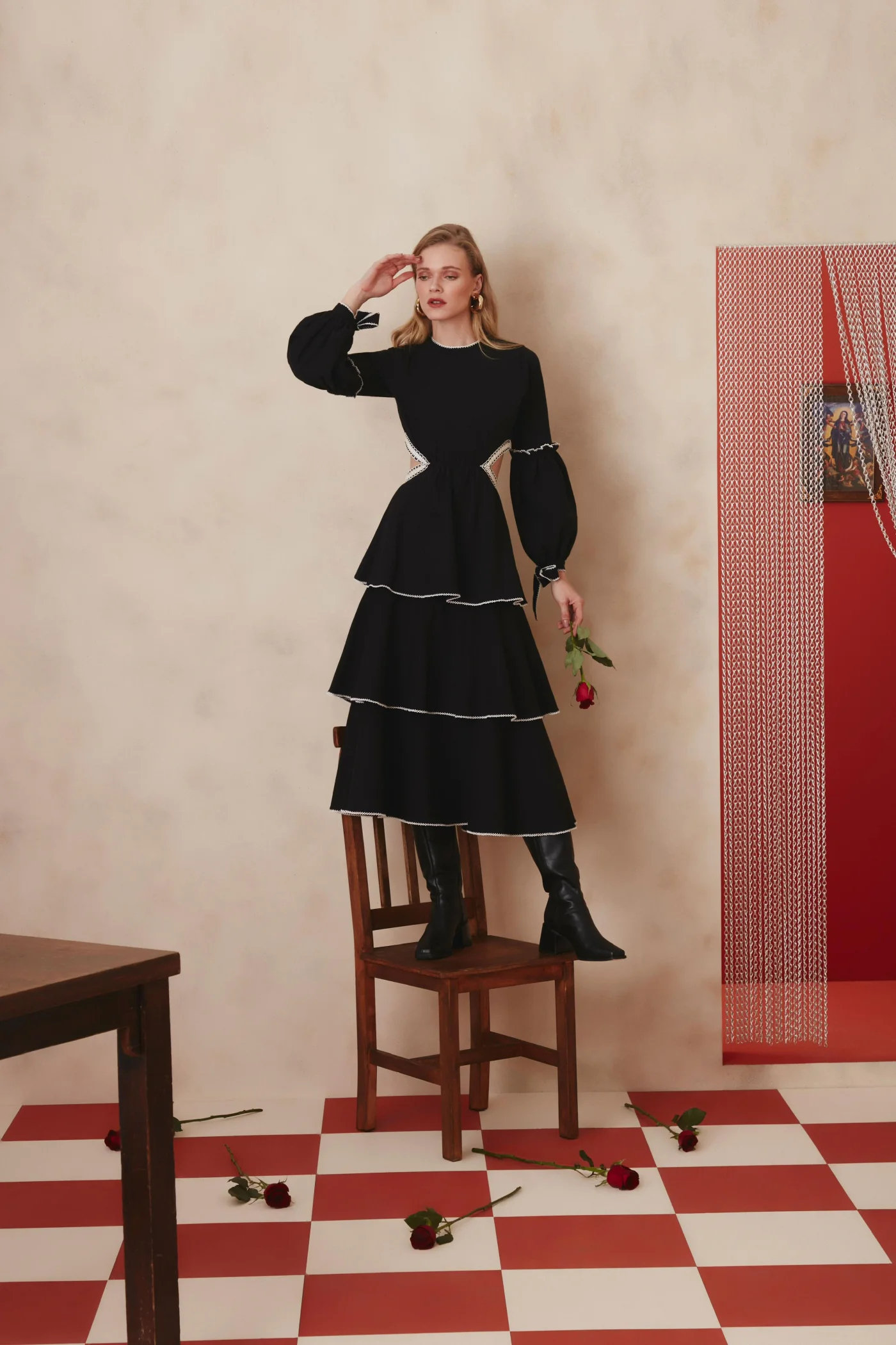 Thais Custodio em vestido preto sobre cadeira no editorial Lalibela
