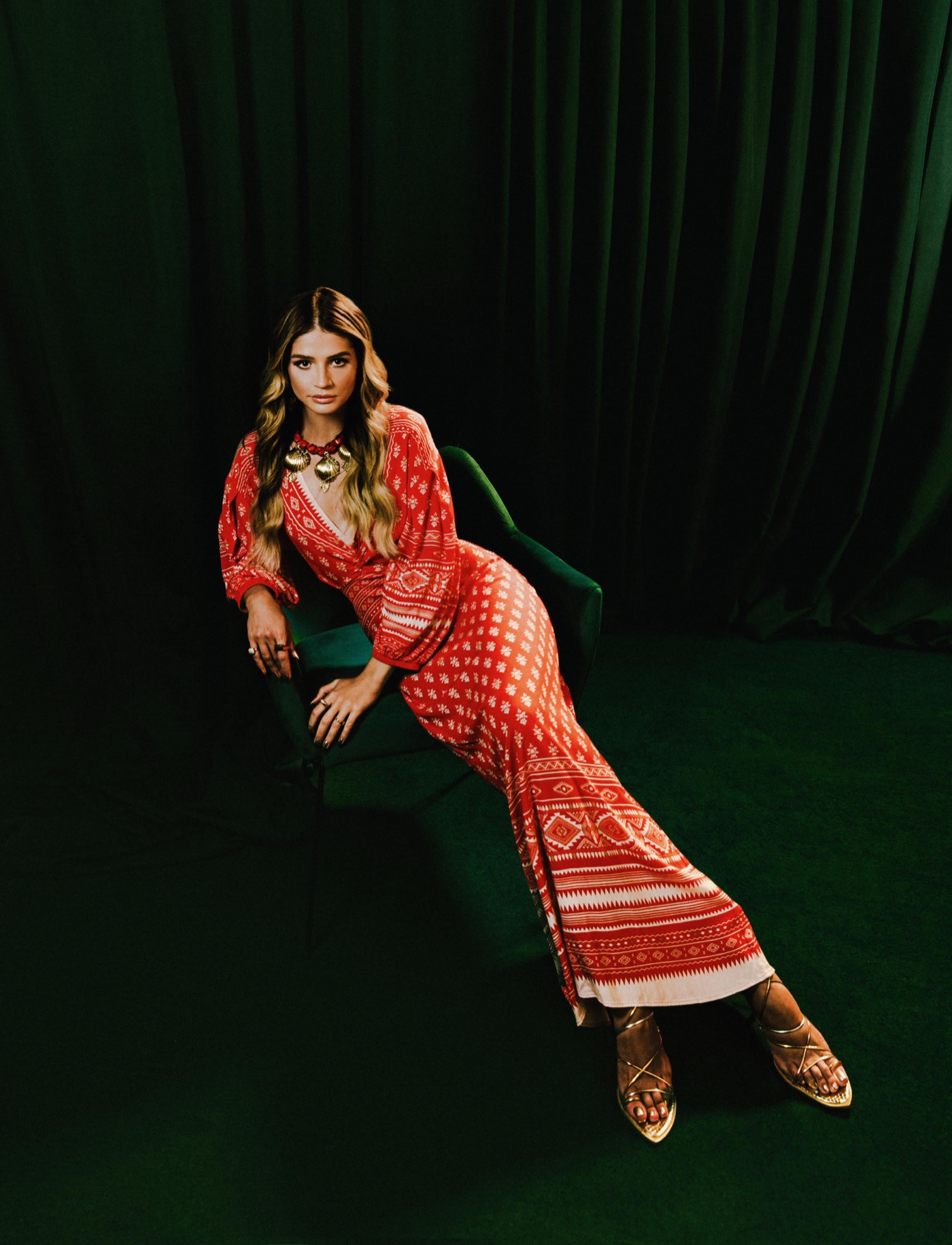 Thássia Naves para Colcci em vestido vermelho sobre cenografia verde com styling de Michael Juvêncio